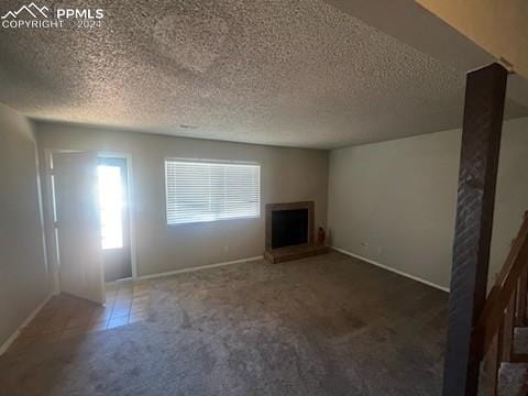 unfurnished living room featuring a textured ceiling and dark colored carpet