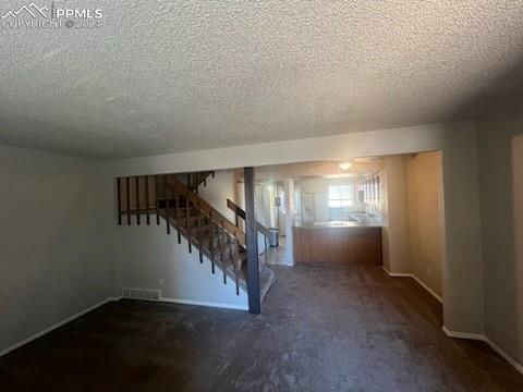 basement with a textured ceiling and dark colored carpet