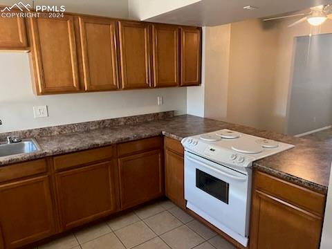 kitchen with sink, electric range, ceiling fan, light tile patterned floors, and kitchen peninsula