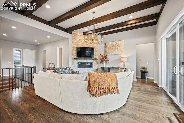 living room featuring hardwood / wood-style flooring, a notable chandelier, beam ceiling, and a fireplace