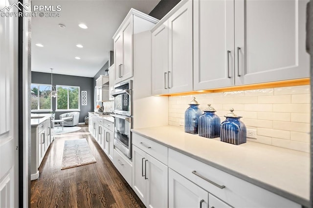 kitchen with pendant lighting, dark hardwood / wood-style floors, white cabinetry, and tasteful backsplash