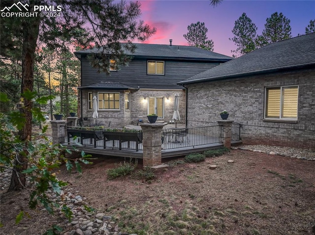 back house at dusk with a wooden deck