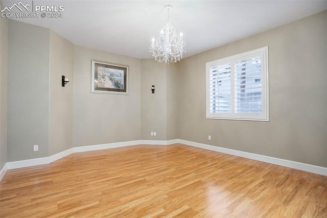 unfurnished room with a chandelier and light hardwood / wood-style floors