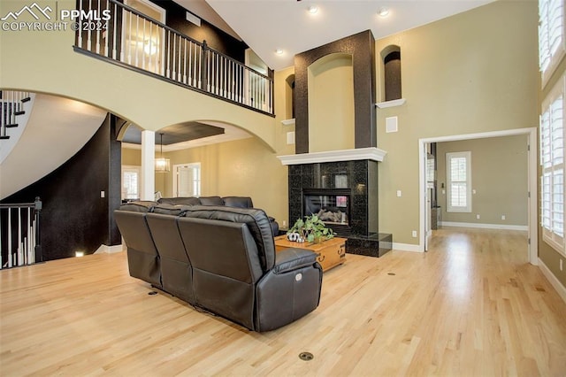 living room featuring hardwood / wood-style floors, a towering ceiling, and a tiled fireplace