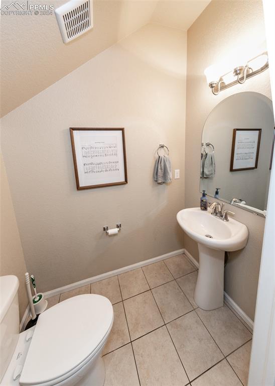 1441 Kempton Aly, Colorado Springs, CO 80910 - half bath featuring toilet, lofted ceiling, tile patterned flooring, and baseboards