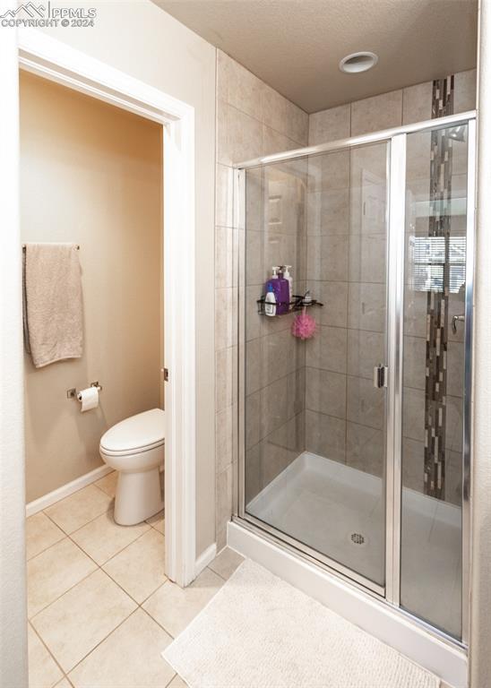 1441 Kempton Aly, Colorado Springs, CO 80910 - bathroom featuring tile patterned flooring, toilet, a stall shower, and baseboards