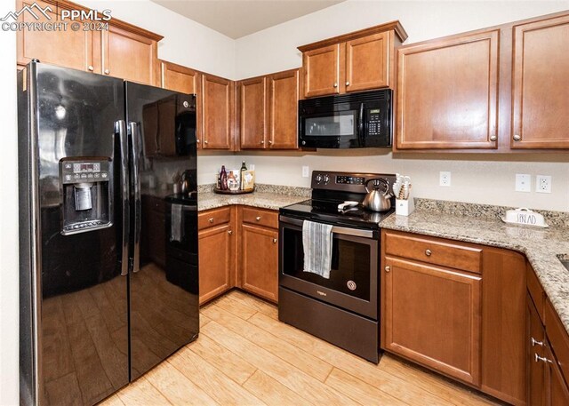 1441 Kempton Aly, Colorado Springs, CO 80910 - kitchen featuring black appliances, light wood-style flooring, brown cabinets, and light stone countertops