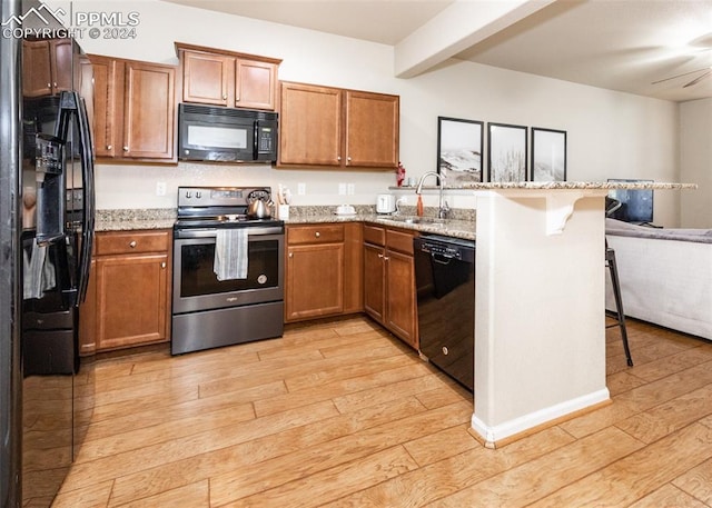 1441 Kempton Aly, Colorado Springs, CO 80910 - kitchen with black appliances, a sink, light wood-style flooring, a peninsula, and beam ceiling