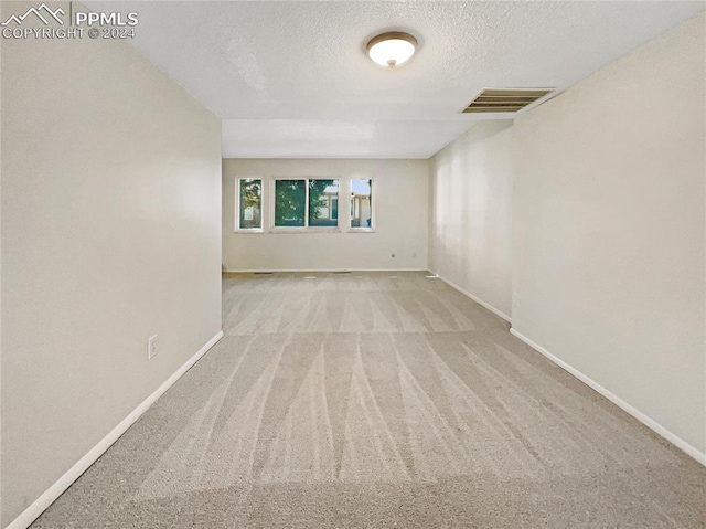 carpeted empty room featuring a textured ceiling