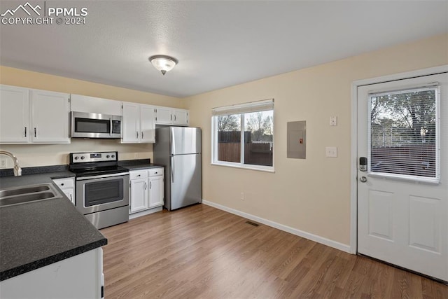 kitchen with stainless steel appliances, sink, hardwood / wood-style flooring, electric panel, and white cabinetry