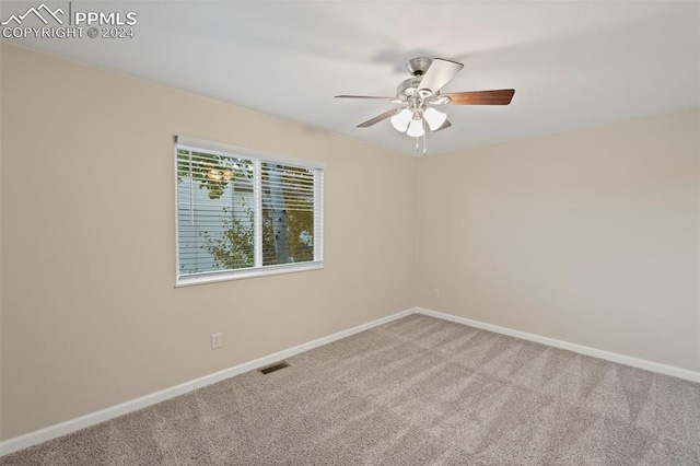 empty room featuring ceiling fan and carpet