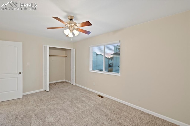 unfurnished bedroom with ceiling fan, light carpet, and a closet