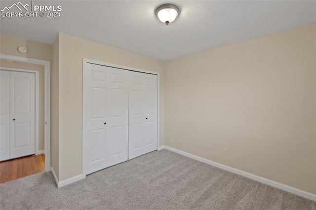 unfurnished bedroom featuring light carpet and a closet