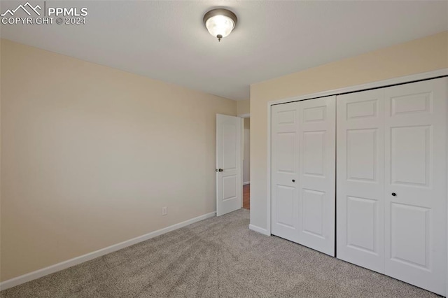 unfurnished bedroom with light carpet and a closet