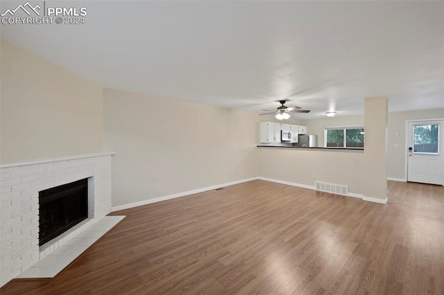 unfurnished living room featuring hardwood / wood-style flooring, ceiling fan, and a fireplace