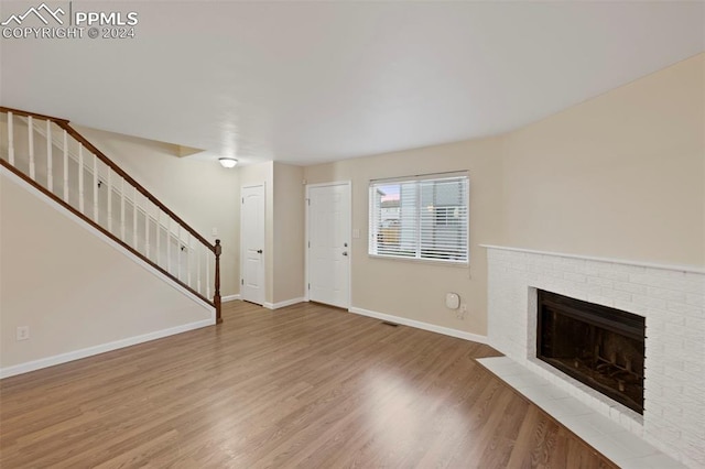 unfurnished living room with hardwood / wood-style flooring and a brick fireplace