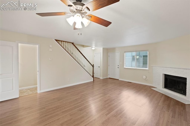 unfurnished living room featuring ceiling fan, light hardwood / wood-style floors, and a brick fireplace