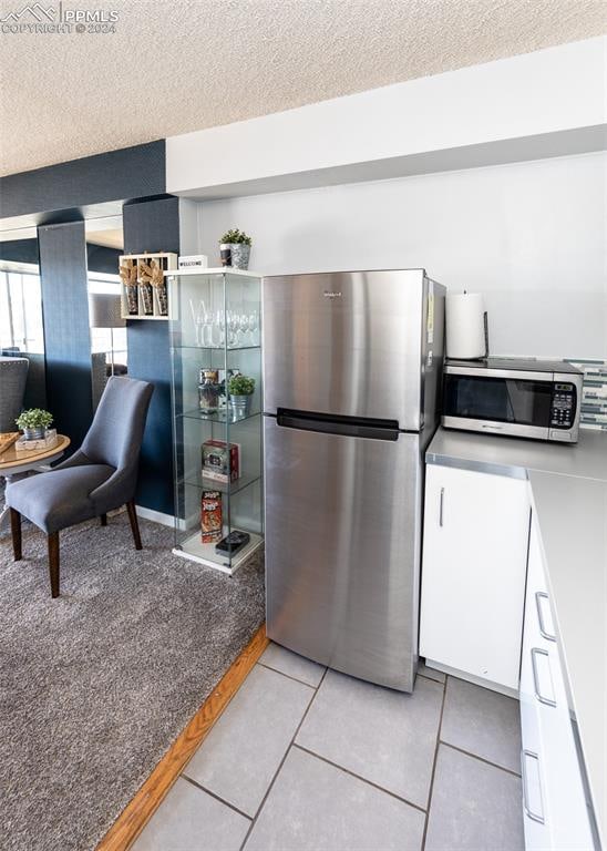 kitchen featuring a textured ceiling, white cabinets, light tile patterned floors, and appliances with stainless steel finishes