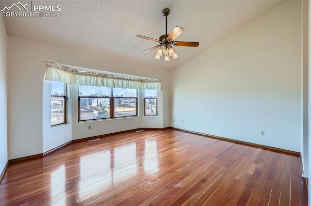 unfurnished room with hardwood / wood-style floors, a textured ceiling, vaulted ceiling, and ceiling fan