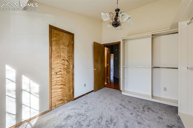 unfurnished bedroom featuring carpet, a closet, and an inviting chandelier