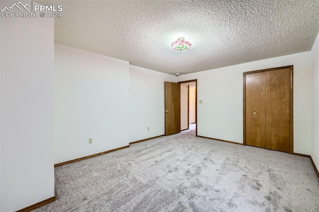 unfurnished bedroom with a textured ceiling, light colored carpet, and a closet