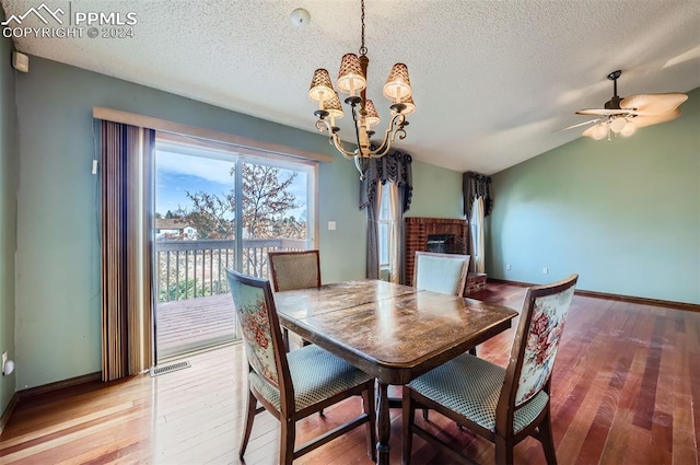 dining area featuring ceiling fan with notable chandelier, wood-type flooring, a textured ceiling, and lofted ceiling