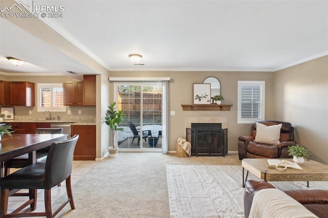 carpeted living room with crown molding, a wealth of natural light, and a tiled fireplace