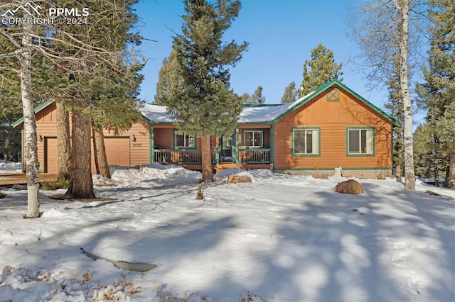 snow covered house with a porch and a garage