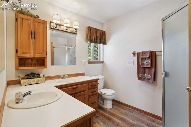 bathroom featuring hardwood / wood-style flooring, vanity, toilet, and an enclosed shower