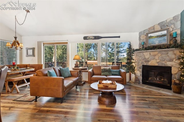 living room with vaulted ceiling, a stone fireplace, dark hardwood / wood-style floors, and a notable chandelier