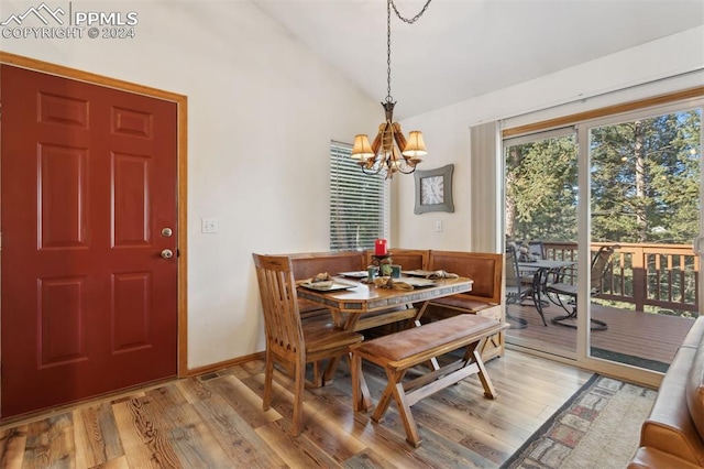 dining space with a notable chandelier, light wood-type flooring, and vaulted ceiling