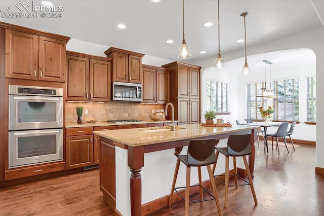 2933 Cathedral Park Vw, Colorado Springs, CO 80904 - kitchen featuring a sink, stainless steel appliances, brown cabinetry, arched walkways, and recessed lighting