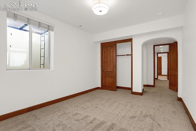 2933 Cathedral Park Vw, Colorado Springs, CO 80904 - unfurnished bedroom featuring arched walkways, light colored carpet, baseboards, and a closet