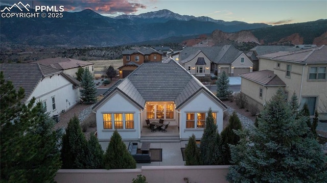 2933 Cathedral Park Vw, Colorado Springs, CO 80904 - back of house at dusk with a mountain view, stucco siding, and a residential view