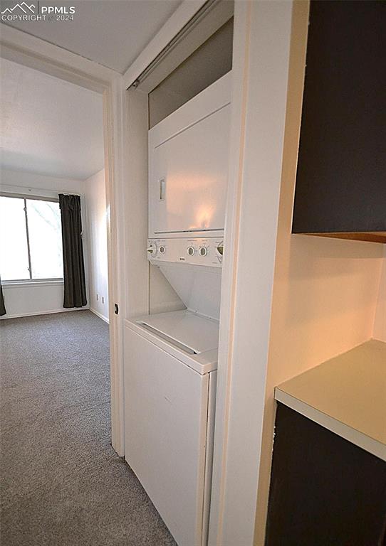 washroom with carpet floors and stacked washer / drying machine