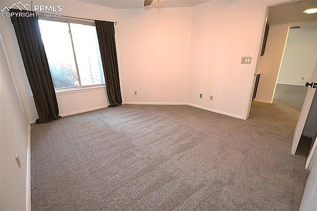 empty room featuring ceiling fan and dark carpet