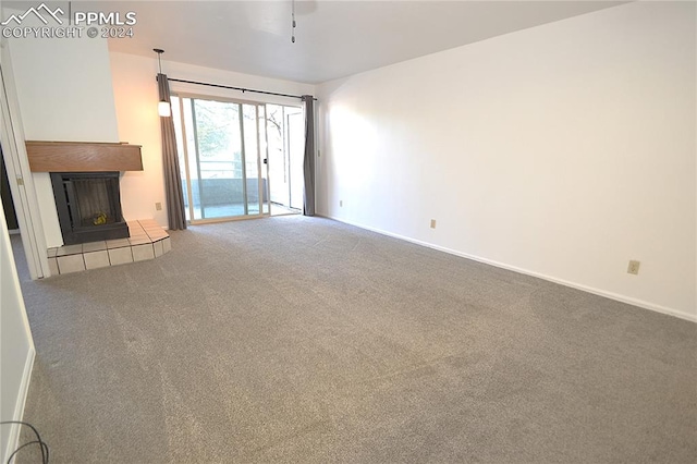 unfurnished living room with a tiled fireplace and carpet