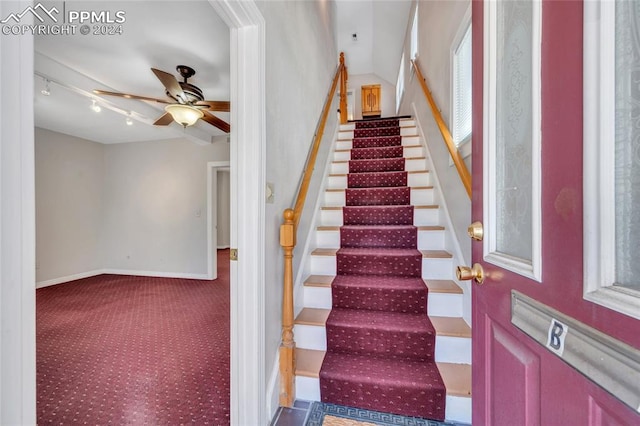 staircase featuring carpet, rail lighting, and ceiling fan