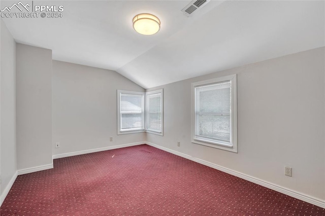 carpeted spare room with vaulted ceiling