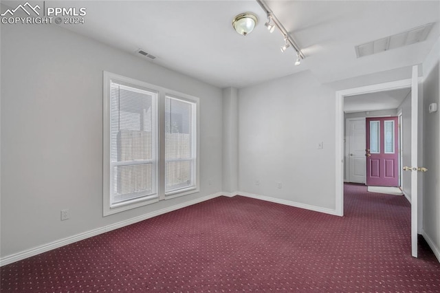 carpeted spare room featuring a wealth of natural light and rail lighting