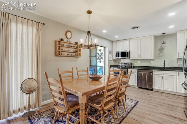 dining room with a notable chandelier, light wood-type flooring, and sink