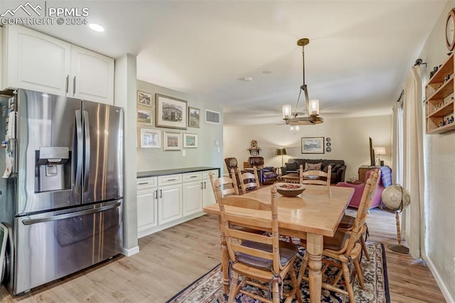 dining space with light hardwood / wood-style floors and a notable chandelier