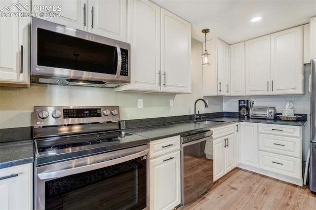 kitchen with pendant lighting, white cabinets, sink, light hardwood / wood-style floors, and stainless steel appliances