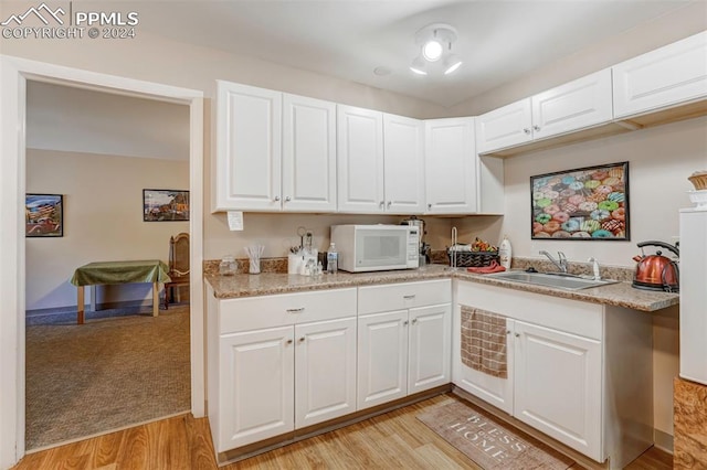 kitchen with white cabinetry, light hardwood / wood-style flooring, and sink