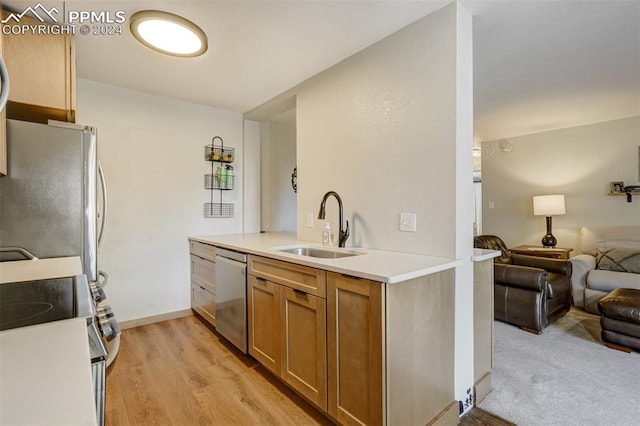 kitchen with kitchen peninsula, light wood-type flooring, sink, and appliances with stainless steel finishes