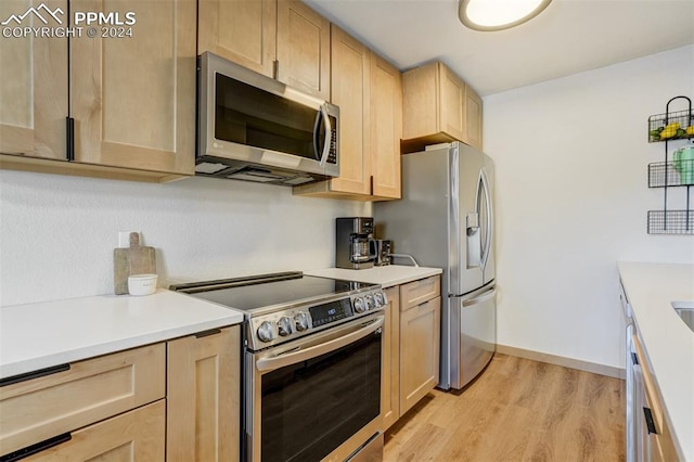 kitchen with light brown cabinets, light wood-type flooring, and appliances with stainless steel finishes