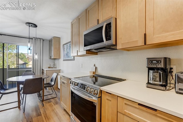 kitchen with light brown cabinets, appliances with stainless steel finishes, and light hardwood / wood-style flooring