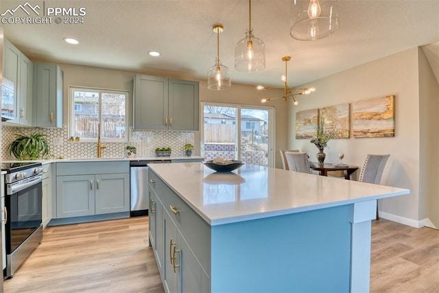 kitchen with hanging light fixtures, stainless steel appliances, light hardwood / wood-style flooring, and plenty of natural light