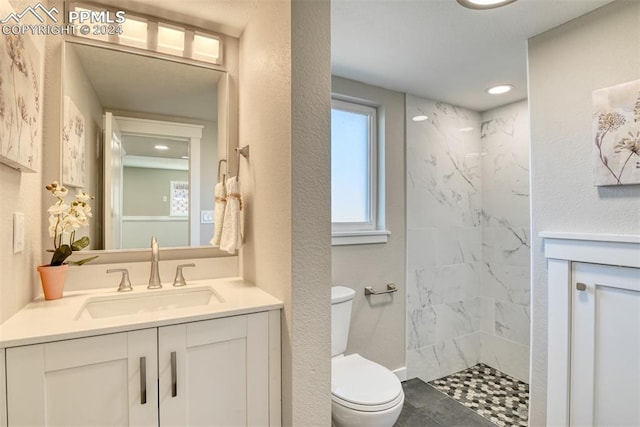 bathroom featuring tile patterned flooring, vanity, toilet, and tiled shower