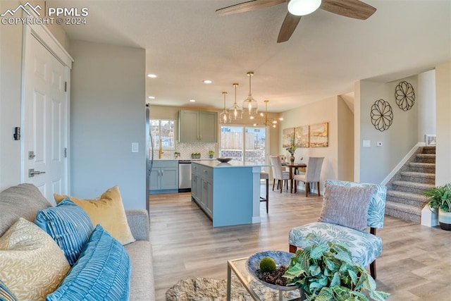 kitchen featuring stainless steel dishwasher, a center island, light wood-type flooring, and backsplash